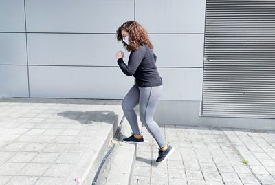 Full length of woman on footpath against wall