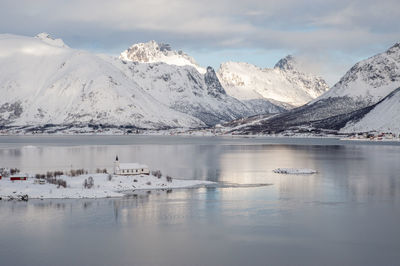 Scenic view of lake by snowcapped mountains against sky