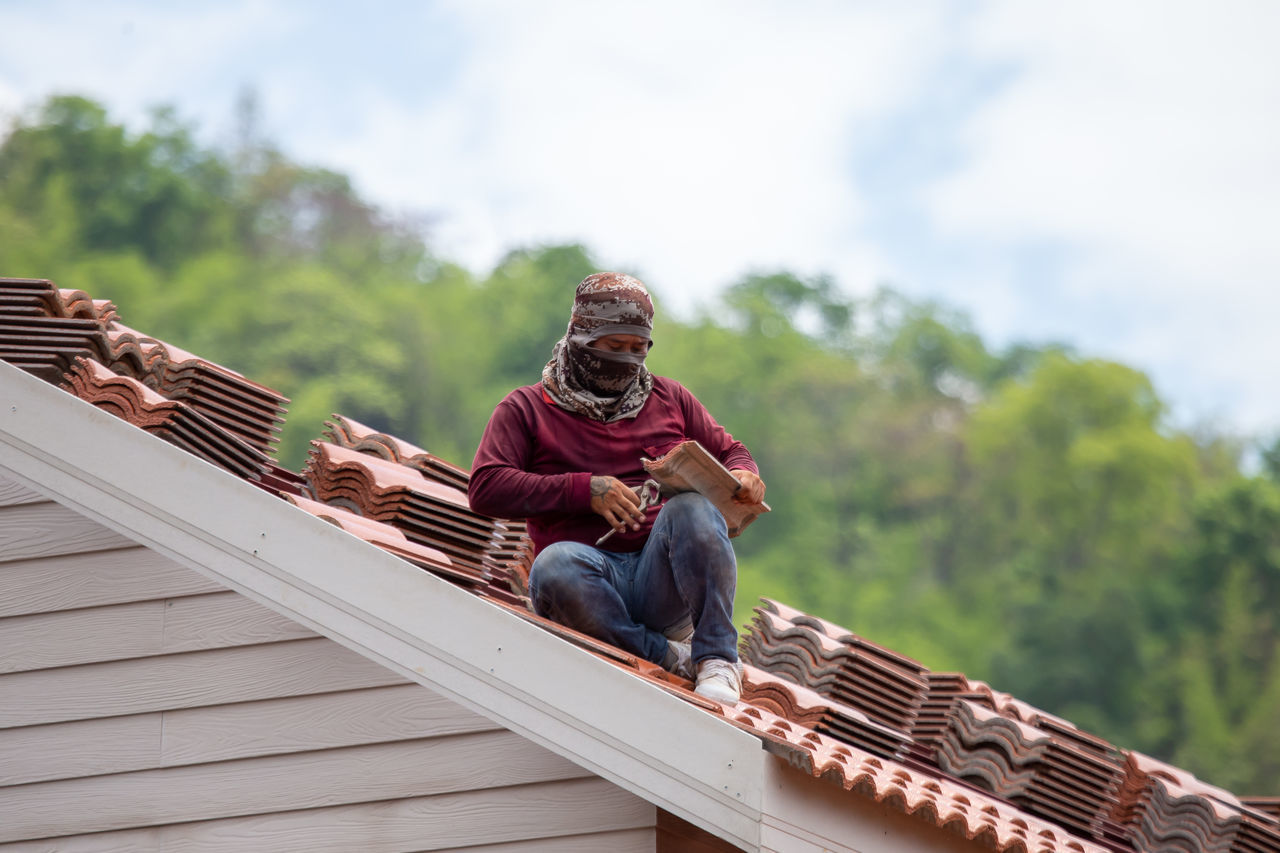 roof, roofer, adult, one person, men, architecture, sitting, nature, sky, occupation, day, built structure, casual clothing, outdoors, wood, full length, hat, relaxation, communication, working, building exterior, happiness, lifestyles, front view, house, activity