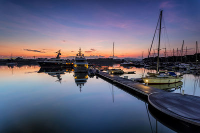 Sailboats moored at harbor against sky during sunset