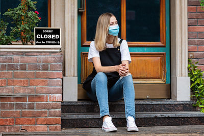 Caucasian waitress woman wearing medical mask and sorry we're closed. coronavirus covid-19 pandemic