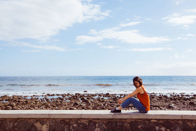 Young woman looking at sea against sky