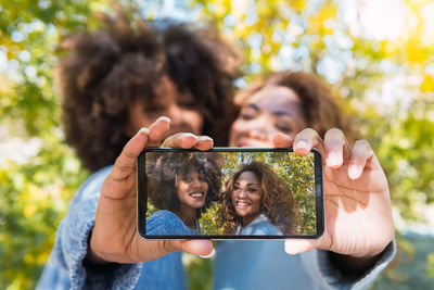 Cheerful afro black friends in a fun mood taking selfie with smartphone using the front camera