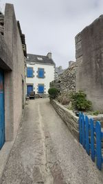 Footpath amidst buildings against sky