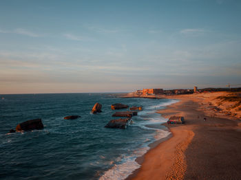 Scenic view of sea against sky during sunset with ruins of bunkers in foreground