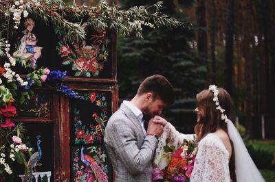 Bridegroom kissing bride hand by plants