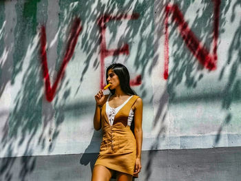 Full length of woman standing against graffiti wall