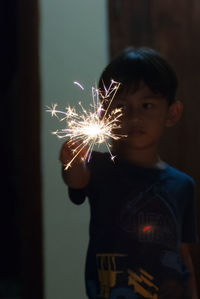 Young boy holding sparkler at night