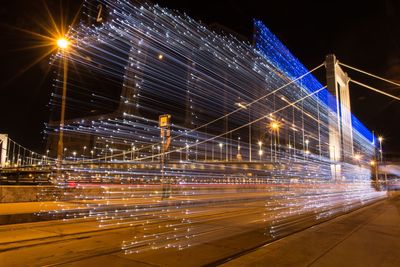 Light trails on tramway against sky at night