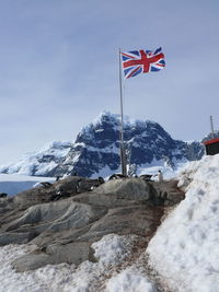 Low angle view of flag on snowcapped mountain against sky