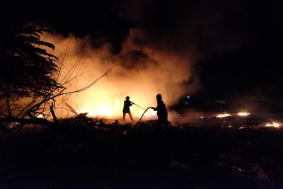 Silhouette of firefighter against sky at night