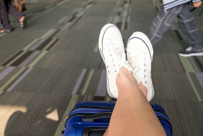 Low section of woman relaxing on luggage