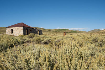 House on field against clear blue sky