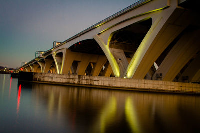 Low angle view of bridge over river against sky at night