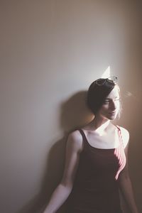 Sunlight falling on thoughtful woman standing against wall