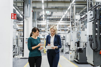 Businesswoman using tablet pc with coworker at factory