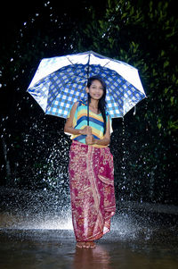 Full length of woman holding wet umbrella during monsoon