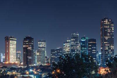 Illuminated cityscape against clear sky at night