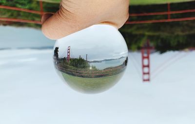 Close-up of person holding glass against sky