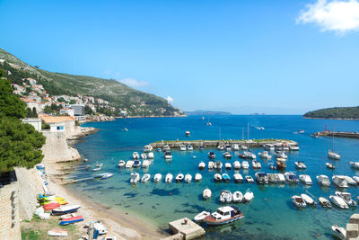 High angle view of boats moored at harbor against blue sky