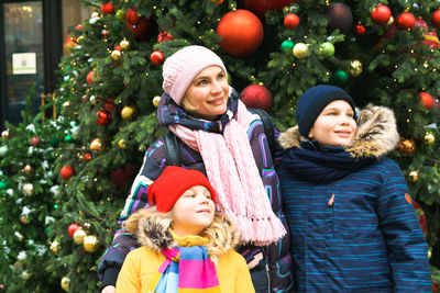 Smiling mother with kids standing by christmas tree