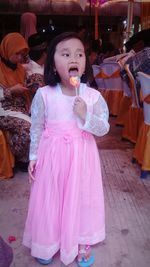 Girl holding pink while standing by outdoors