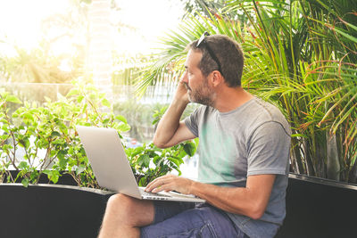 Business man works with laptop sitting at outdoor. male at computer work online with remote office