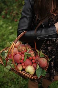 Midsection of woman holding strawberries in basket on field