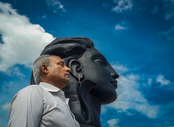 Side view of man standing against shiva statue 