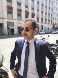 Young man wearing sunglasses while standing in city