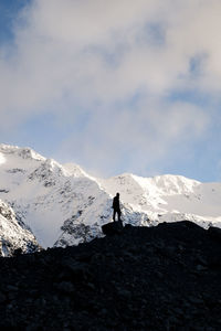 Man standing on snowcapped mountain against sky