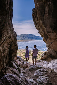 Rear view of women on rock by sea against sky