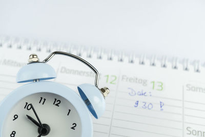 High angle view of alarm clock and calendar against gray background