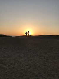 Silhouette people standing on land against sky during sunset