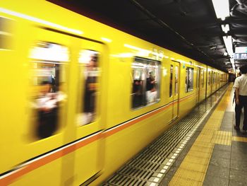 Blurred motion of train at illuminated railroad station at night