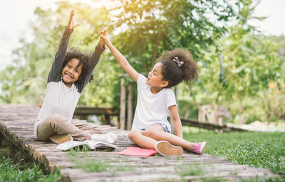 Happy girl playing on grass against trees