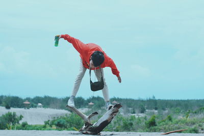 Young man balancing on driftwood and beach 