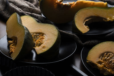 Pieces of sliced pumpkin on the dark table with dark dishes