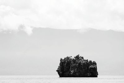 Rock formation in sea against sky