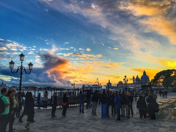 People on street against sky during sunset