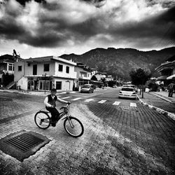 Man riding bicycle on street against buildings in city