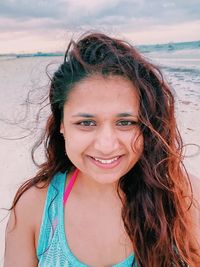 Portrait of woman with tousled hair standing at beach