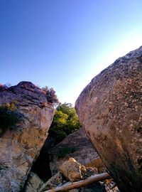 Rock formation amidst trees against clear sky