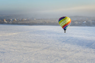 Hot air balloon flying over snow covered field