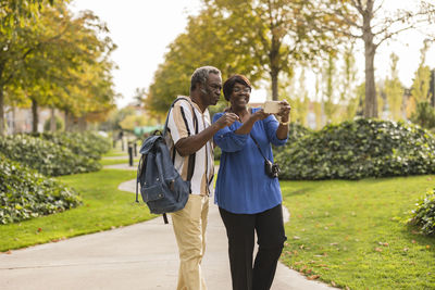 Senior couple using mobile phone standing in park