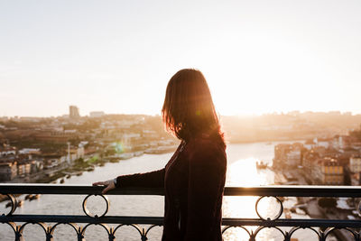 Back view of relaxed woman in porto bridge at sunset. tourism in city europe. travel and lifestyle