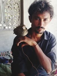 Portrait of young man with bird at home