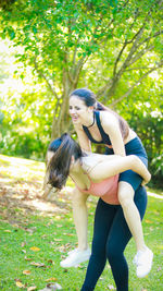 Young woman giving piggyback to friend at park