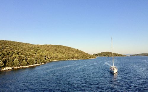 Sailboats sailing in sea against clear blue sky