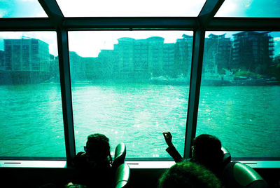 Man photographing woman sitting by window at sea